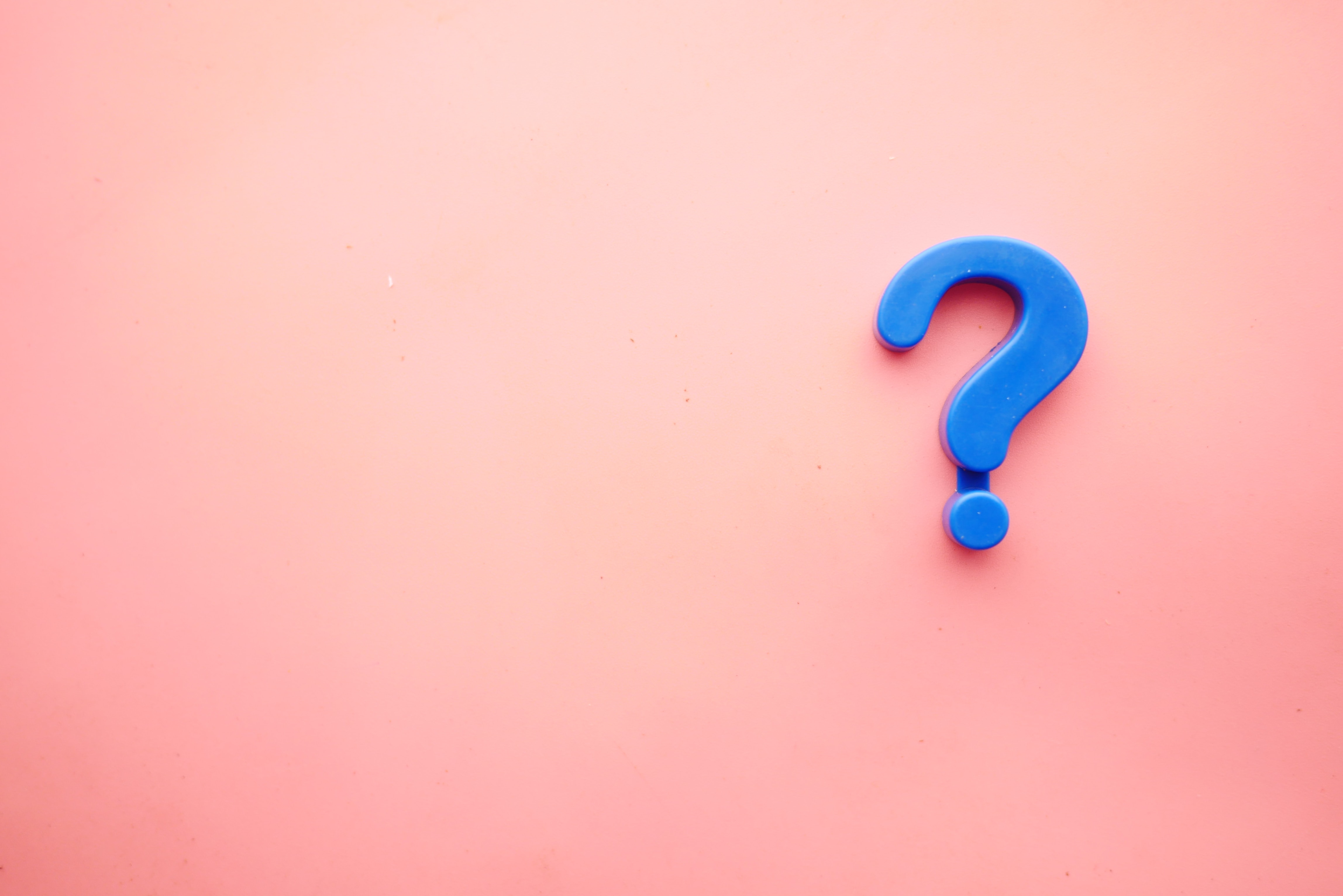 Grande punto interrogativo blu su sfondo rosa che rappresenta le FAQ di Coverflex