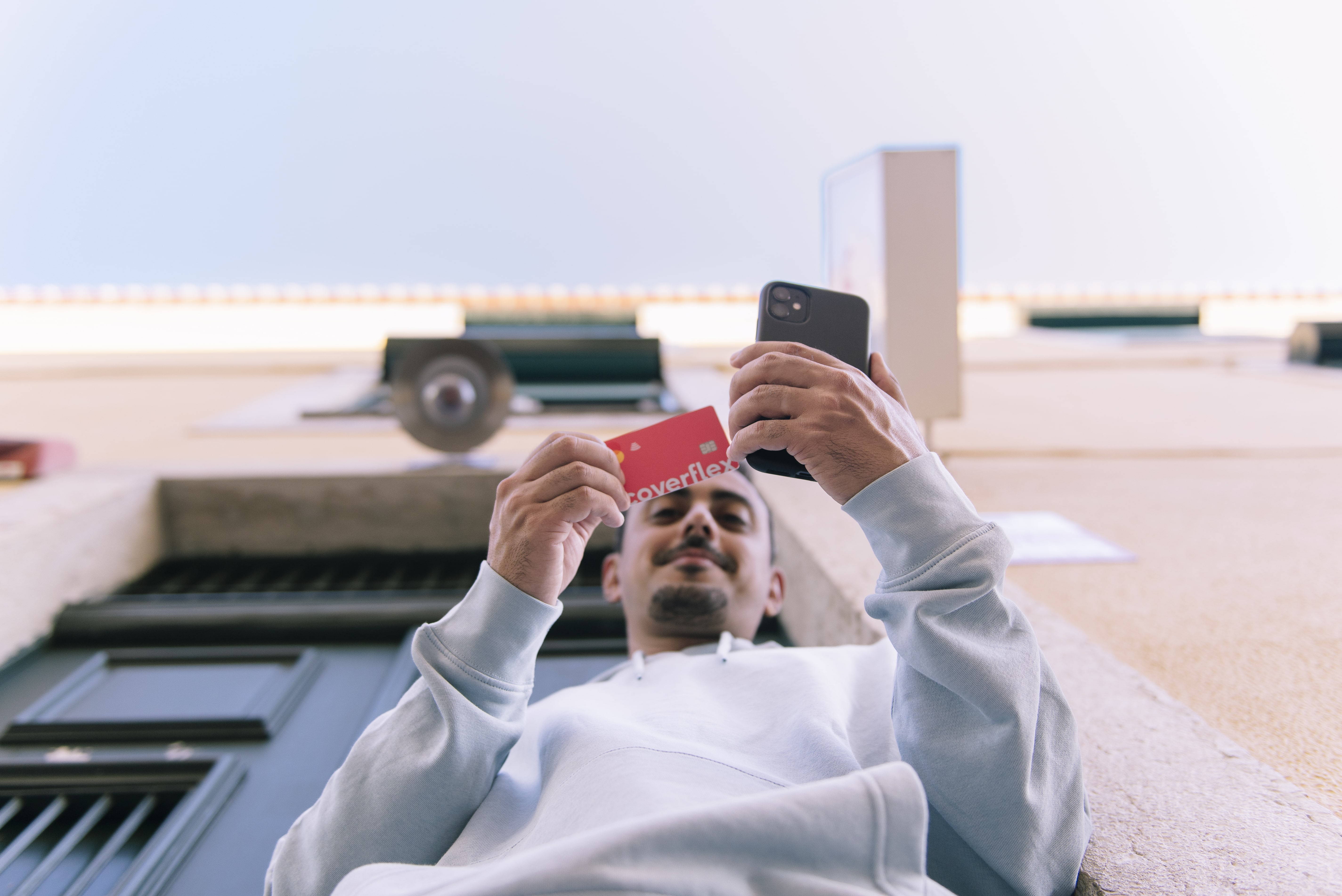 homem a segurar cartão Coverflex vermelho e smartphone