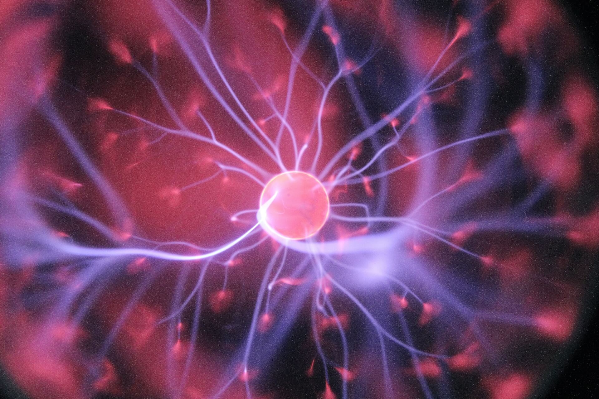 globo de plasma iluminado mostrando descargas elétricas rosa e roxo que se estendem em filamentos desde um núcleo central evocando redes neurais e interconexões sociais