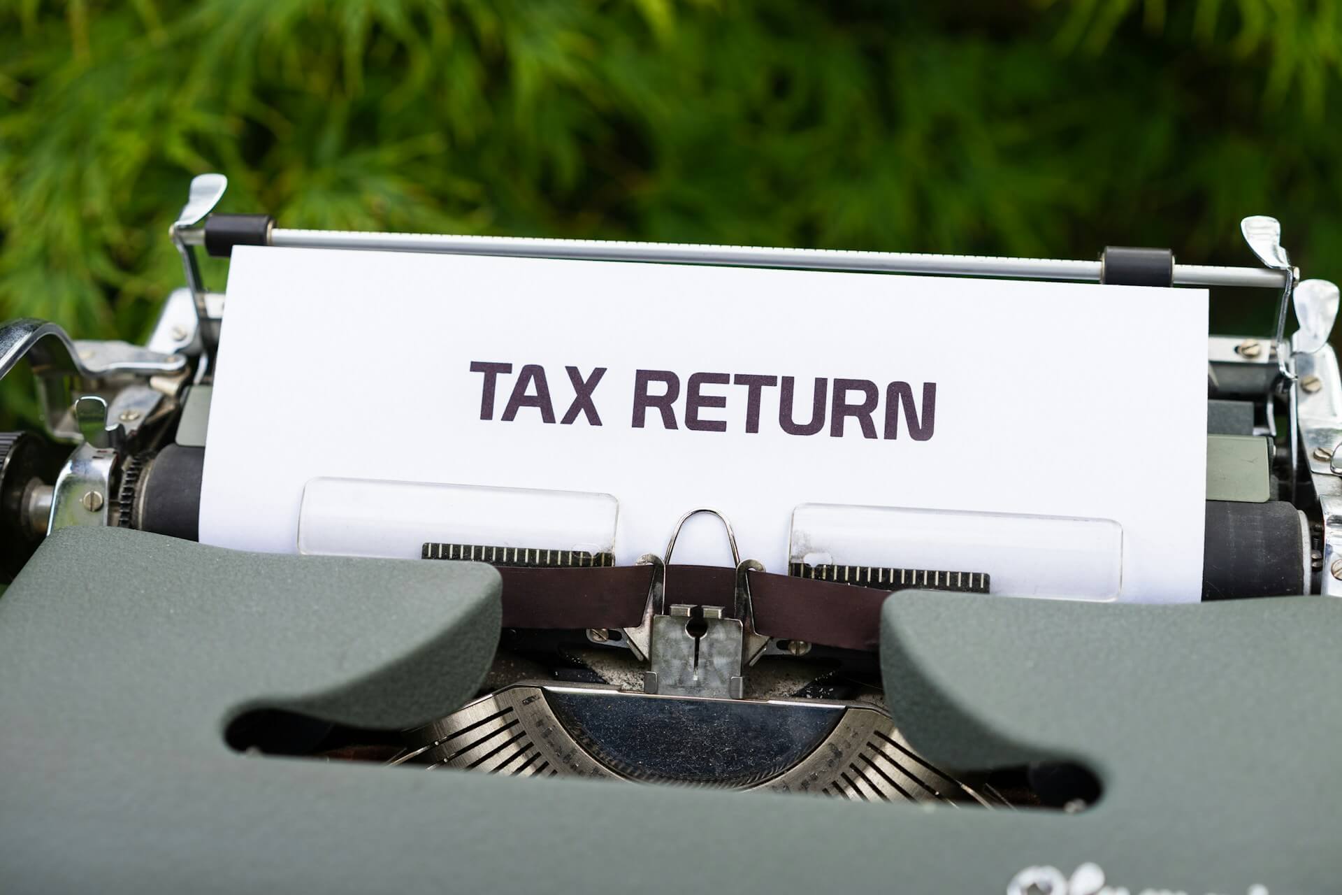 Close up of a typewriter with a white sheet displaying the text tax return, symbolizing tax filing or IRS documentation