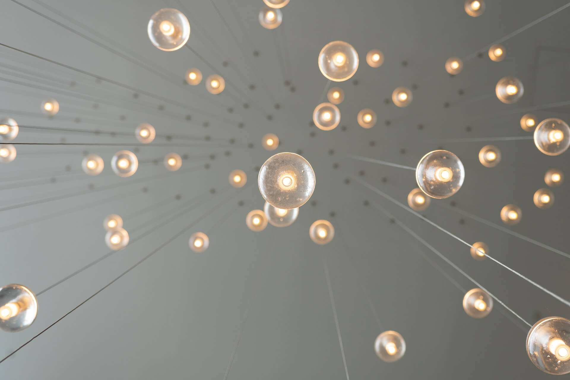 low angle perspective of spherical pendant lights suspended by wires forming a floating array