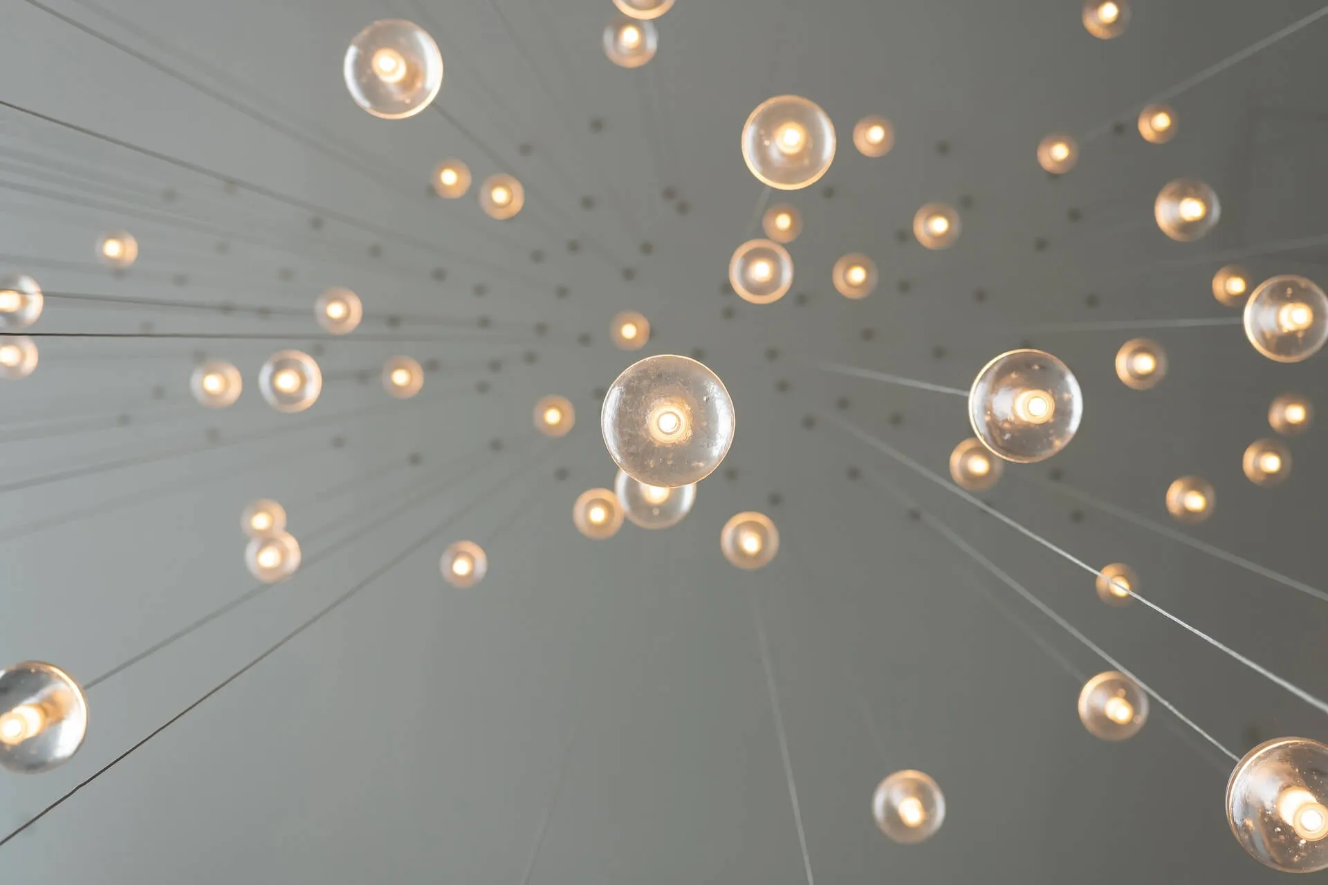 low angle perspective of spherical pendant lights suspended by wires forming a floating array