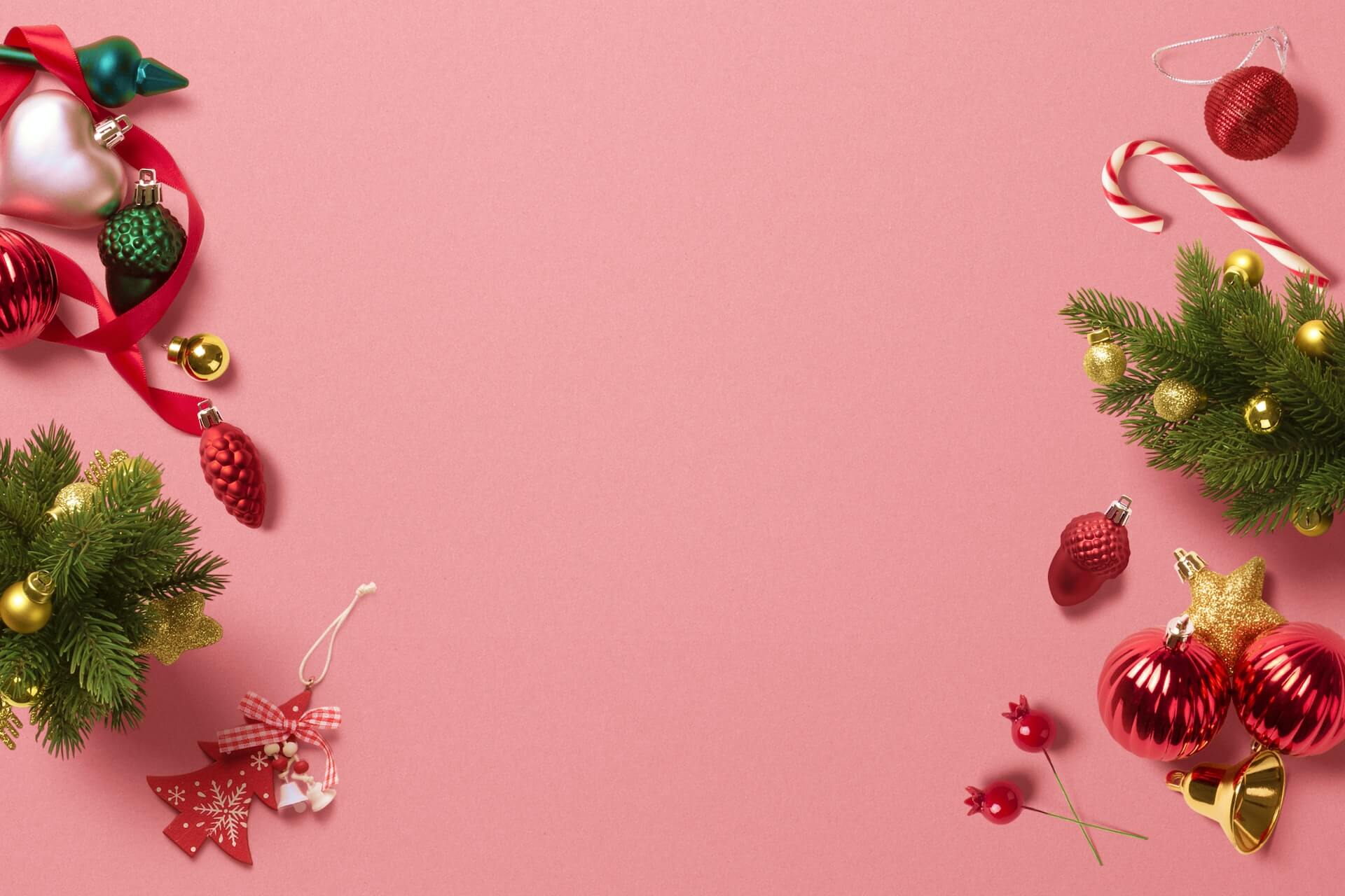 Pink background bordered by fir sprigs, red and gold baubles, ribbon, a candy cane and assorted Christmas decorations