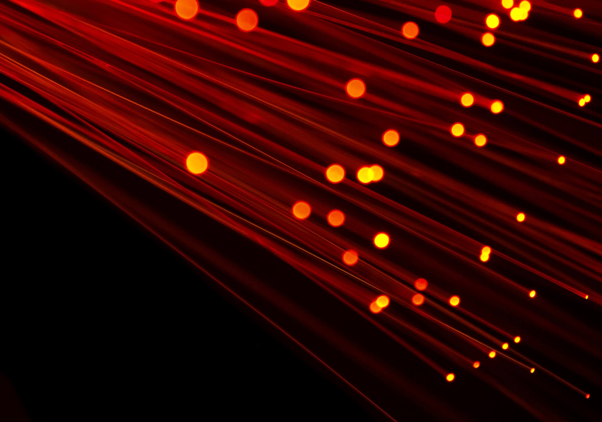 diagonal red and orange glowing fiber optic light streaks over black background creating dynamic abstract effect