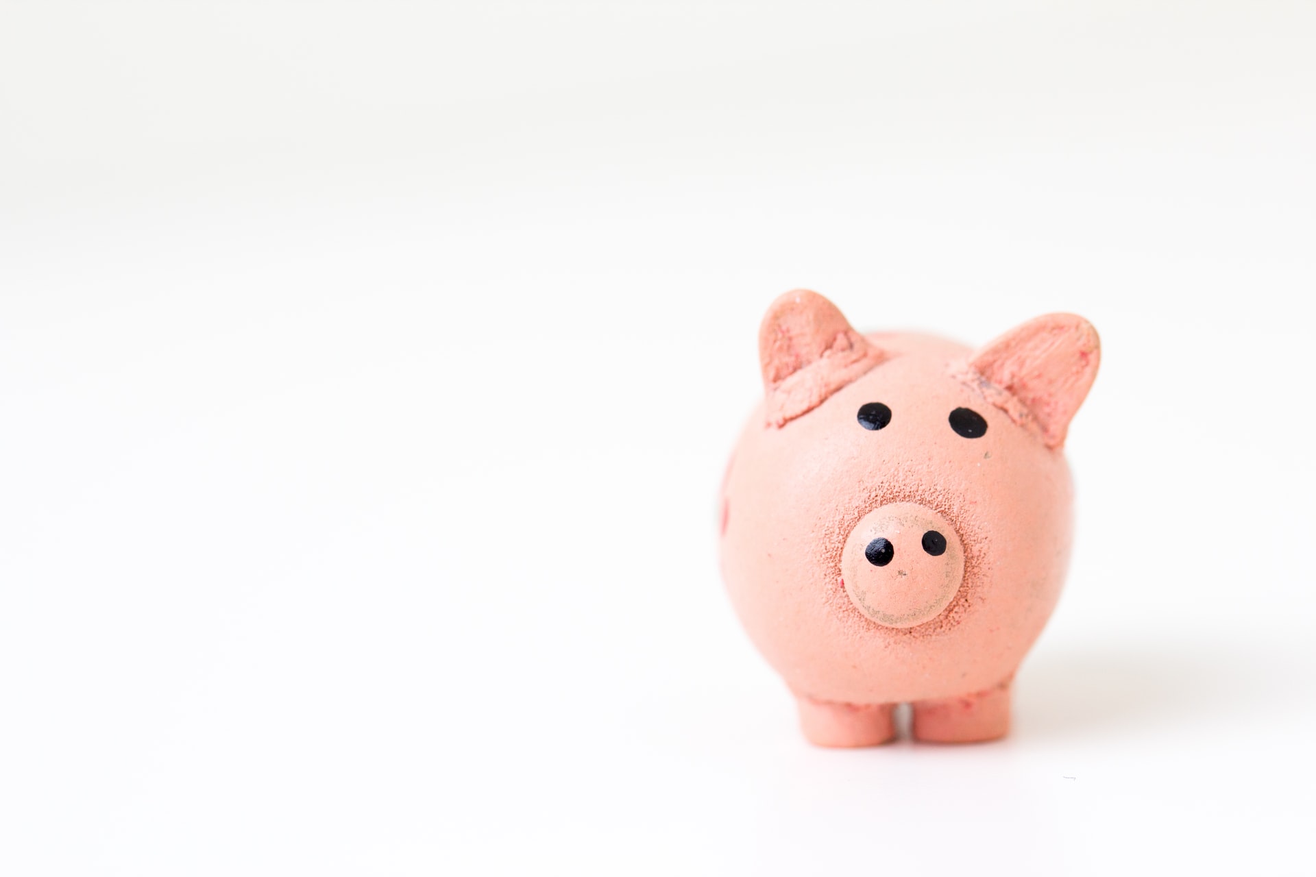 Close-up of a small pink piggy bank on a white surface symbolizing personal finance and savings