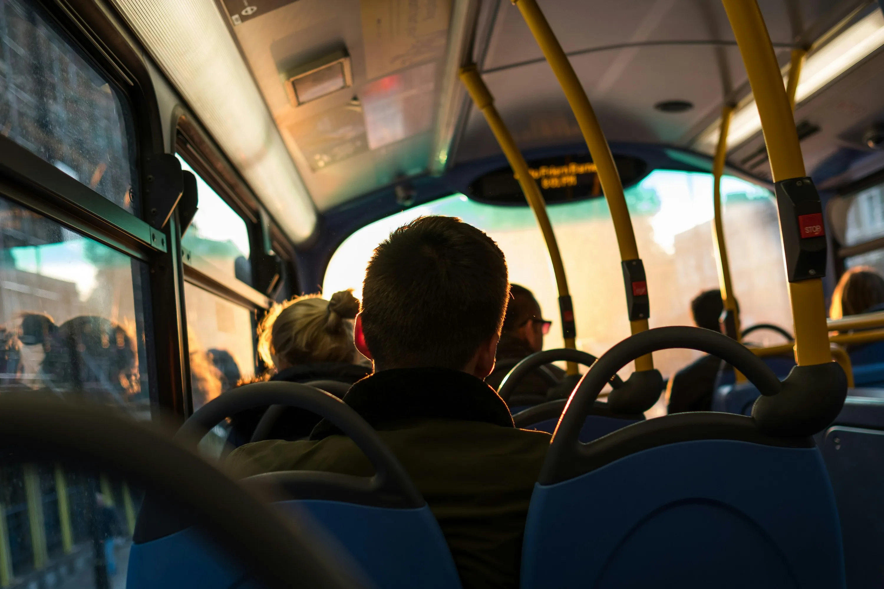 Interior de un autobus con pasajeros sentados de espaldas bajo la luz calida del atardecer