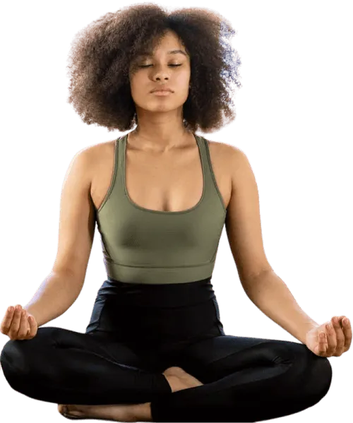 Woman with curly hair meditating in a cross-legged seated yoga pose with eyes closed.